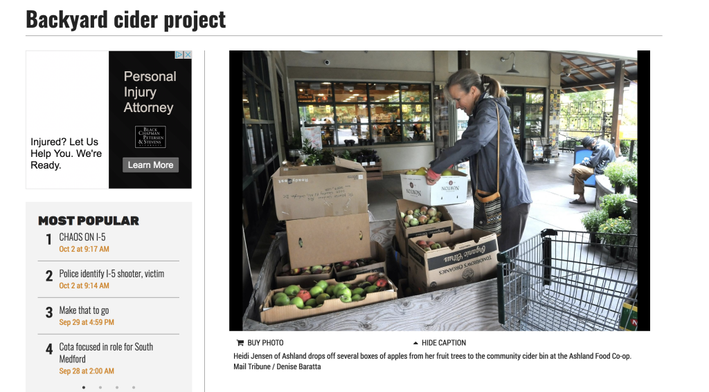 A woman is standing in front of a box of produce.